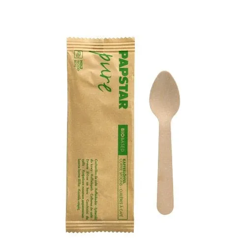 Ein umweltfreundlicher PAPSTAR Kaffeelöffel aus Holz, 11 cm, einzeln in Schrumpffolie verpackt, liegt neben seiner "pure"-Verpackung mit grüner Schrift der Marke PAPSTAR GmbH auf schlichtem, weißem Hintergrund.