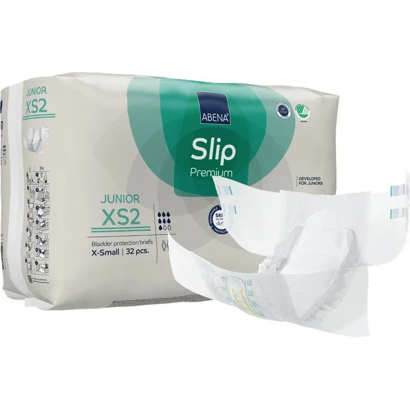 Eine Packung ABENA Slip Junior Premium Gr XS2 von Abena Re-Seller GmbH (32 Stück) wird mit einem Inkontinenzprodukt Kinder Slip neben der grün-weißen Verpackung ausgestellt.
