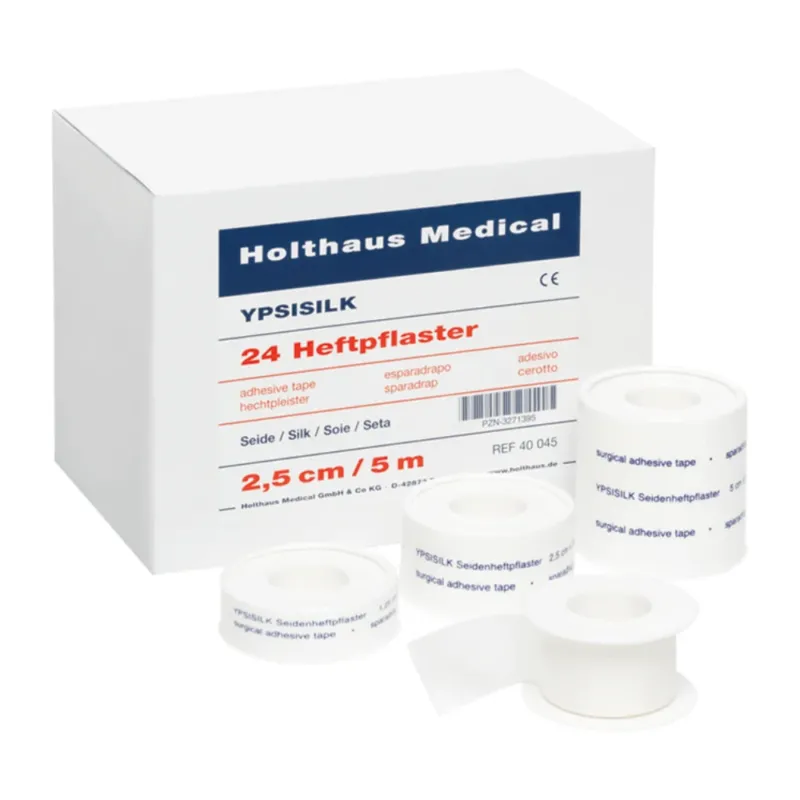 Eine Schachtel mit der Aufschrift „Holthaus Medical GmbH & Co. KG“ mit „Holthaus YPSISILK Heftpflaster – 2,5 cm x 5 m | Packung (5 m)“ und mehreren Rollen weißem Klebeband in verschiedenen Größen davor. Der Text auf der Schachtel und den Bändern enthält Produktdetails in mehreren Sprachen.